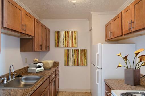 A kitchen with brown cabinets and a painting on the wall at Hummingbird Pointe & The Gardens, Parma