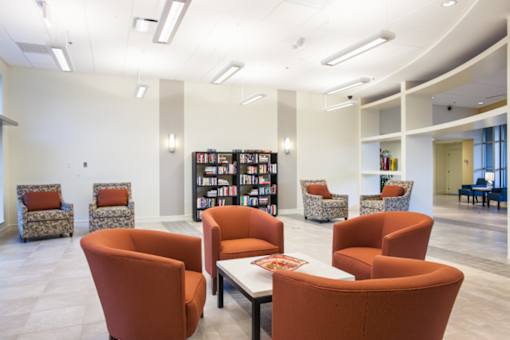 A room with orange chairs and a white table at Hummingbird Pointe & The Gardens, Parma, OH