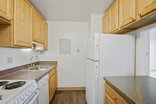 A kitchen with white appliances and wooden cabinets at Independence Place Apartments, Ohio 44130