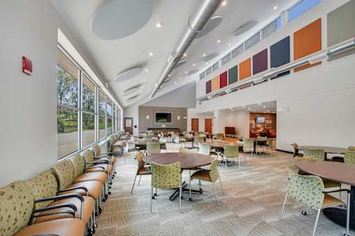 A large room with tables and chairs and a fire extinguisher on the wall at Independence Place Apartments, Parma Heights, OH