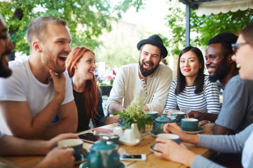 a group of people sitting around a table drinking coffee