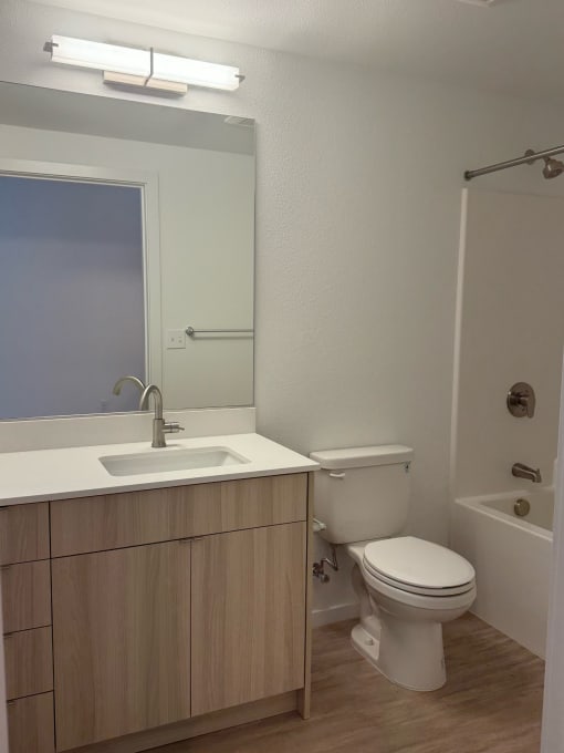 a bathroom with a toilet and a sink and a mirror at Junction Central, Seattle, WA 98116