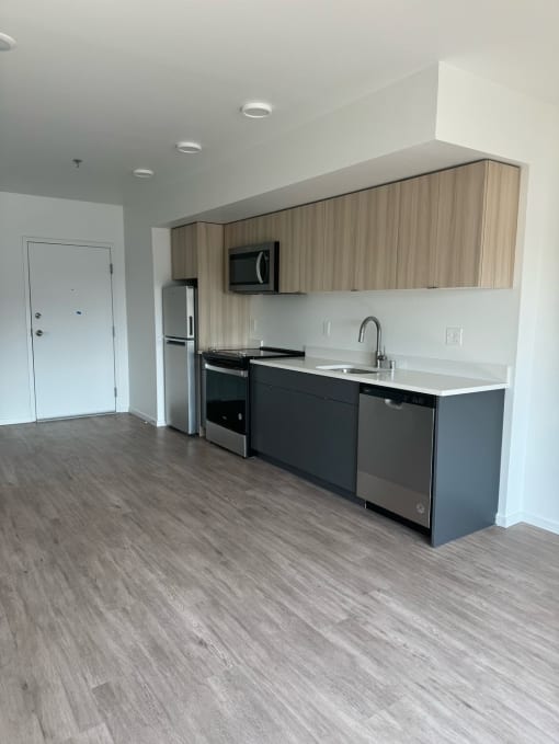 a kitchen in an empty apartment with a sink and refrigerator at Junction Central, Seattle, WA