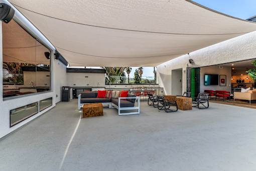 A modern outdoor seating area with a white canopy and concrete floor.