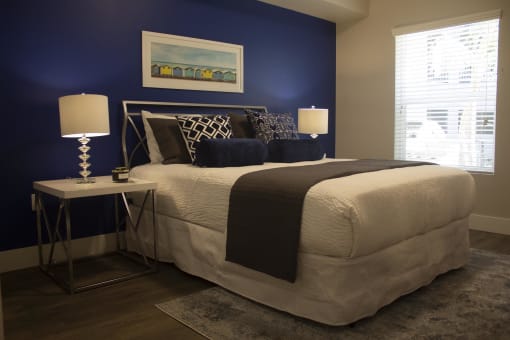 a bedroom with a blue accent wall and a white bed with a black and white comfort at The Crossings at Redlands, California, 92374