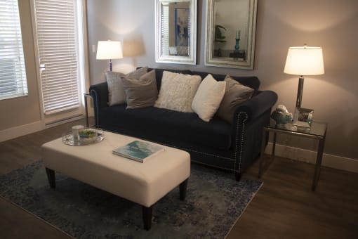 a living room with a black couch and a white ottoman at The Crossings at Redlands, Redlands