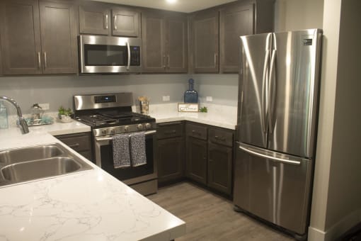 a kitchen with dark cabinets and white countertops at The Crossings at Redlands, California, 92374