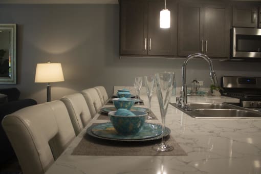 a long kitchen table with white chairs and a sink at The Crossings at Redlands, Redlands, 92374