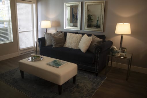a living room with a black couch and a white ottoman at The Crossings at Redlands, California