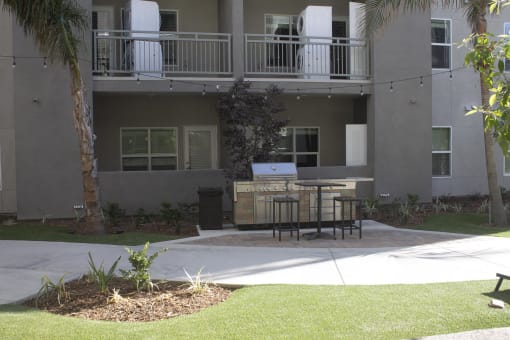 a patio with a grill and table in front of an apartment building at The Crossings at Redlands, Redlands, CA, 92374