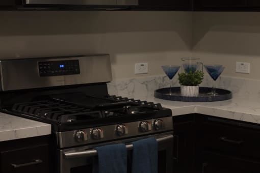 a kitchen with a stove top oven next to a counter at The Crossings at Redlands, Redlands, CA, 92374