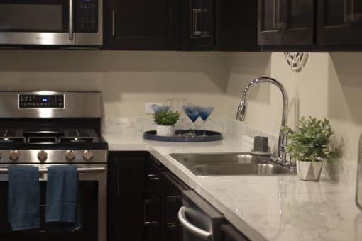 a kitchen with black cabinets and white marble countertops at The Crossings at Redlands, Redlands, CA
