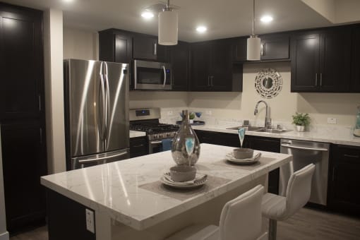 a kitchen with black cabinets and a white island at The Crossings at Redlands, California, 92374