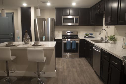 a kitchen with dark cabinets and white countertops at The Crossings at Redlands, Redlands