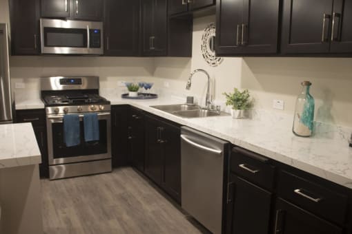 a kitchen with black cabinets and white countertops at The Crossings at Redlands, California, 92374