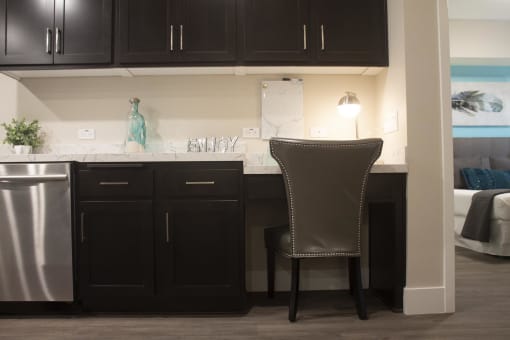 a kitchen with black cabinets and a white counter top with a chair in front of it at The Crossings at Redlands, Redlands, CA