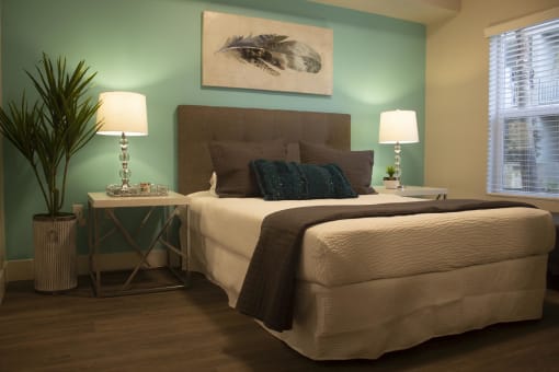 a bedroom with a green accent wall and a bed with a brown headboard at The Crossings at Redlands, California