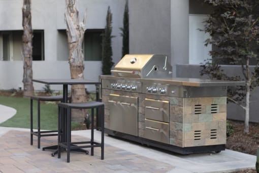 an outdoor kitchen with a grill and a table and chairs at The Crossings at Redlands, Redlands, 92374