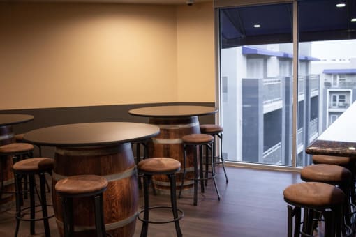 a bar area with wooden tables and stools and a large window with a view of a at The Crossings at Redlands, Redlands, 92374