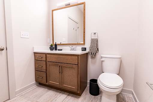 A bathroom with a toilet, sink, and mirror.