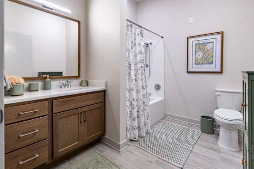 A bathroom with a white toilet, a sink with a mirror above it, and a shower with a curtain.