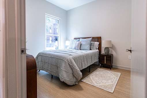 A bedroom with a bed, nightstand, and window.