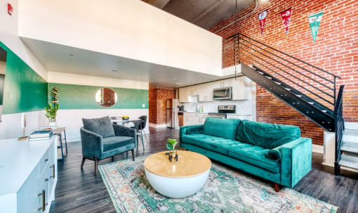 a living room with a turquoise couch and a table and a staircase