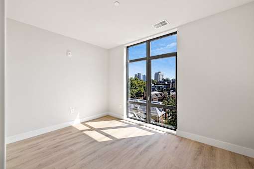 an empty living room with a large window and wooden floors