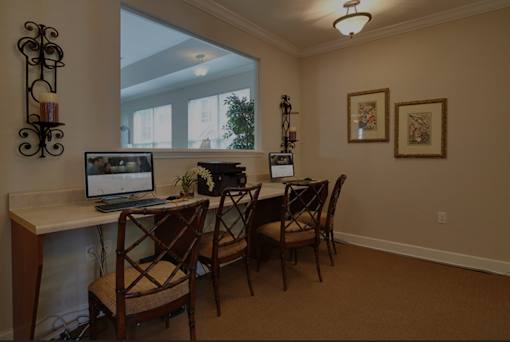 A room with a desk, chairs, and a laptop.
