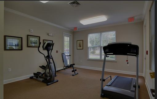A room with a treadmill, a stationary bike, and a weight machine.