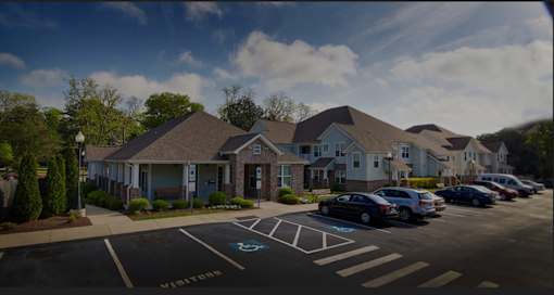 A parking lot in front of a building with cars parked.