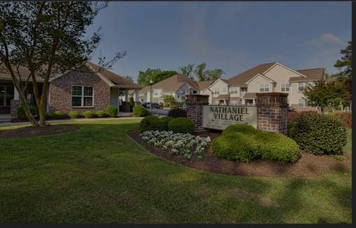 A sign that says Nathaniel Village is in front of some houses.