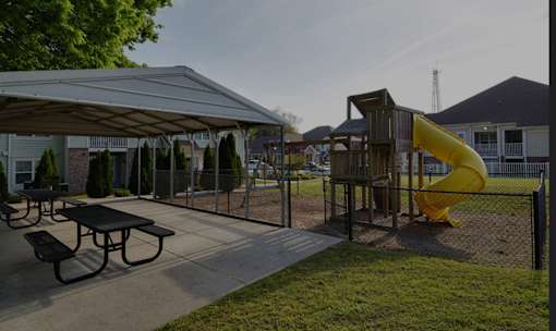 A playground with a yellow slide and picnic tables.
