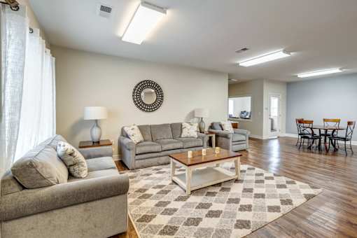 A living room with a couch, a coffee table, and a dining table. at Ada Park Apartments, Newport News, VA