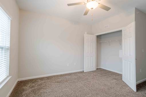 A room with a ceiling fan and a closet.