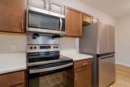 A kitchen with a stainless steel refrigerator and a black oven.