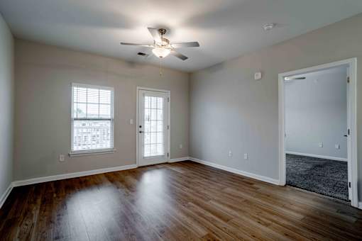 A room with a ceiling fan and wooden floors.