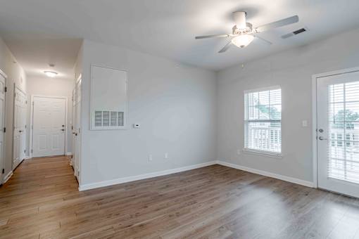 A spacious room with a ceiling fan and hardwood floors.
