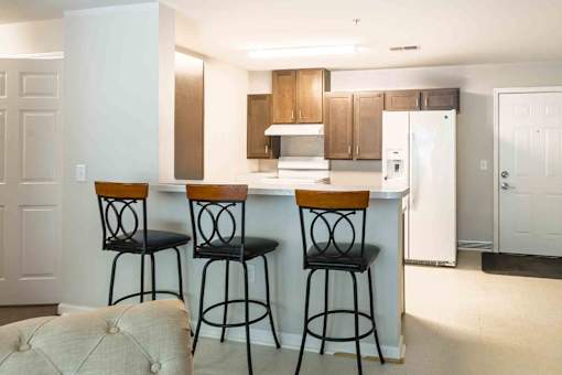 A kitchen with a white refrigerator and brown bar stools. at Bickerstaff Crossing Apartments, Virginia