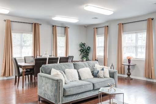 A living room with a grey couch, a dining table, and a coffee table.