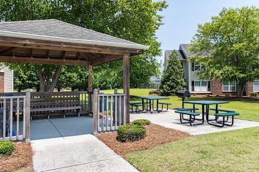 A pavilion with picnic tables is surrounded by a fence and a sidewalk at Carriage Hills, Lumberton
