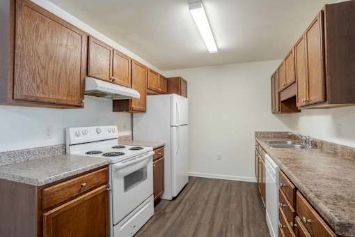 A kitchen with white appliances and wooden cabinets at Carriage Hills, Lumberton, NC 28358