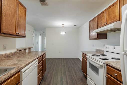 A kitchen with white appliances and wooden cabinets at Carriage Hills, Lumberton, NC 28358