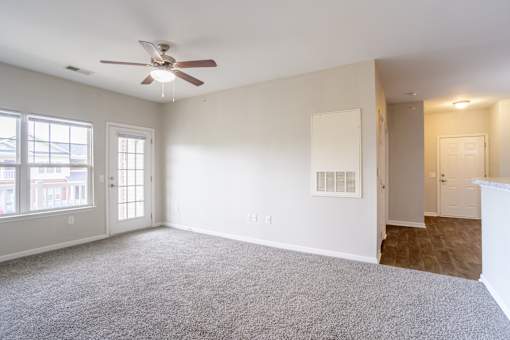 Open living area with ceiling fan, plush carpet, and view into hallway and entry, providing functional flow at Cedar Terrace Apartments Hendersonville, NC