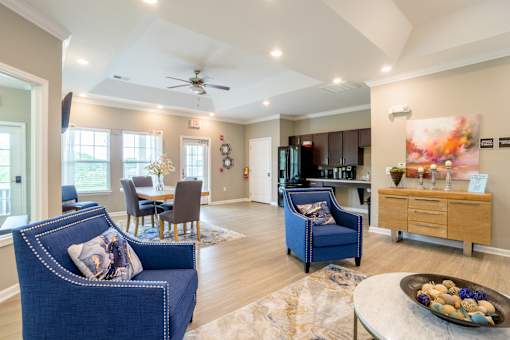 Elegant resident clubhouse with modern furnishings, dining table, lounge seating, and full kitchenette at Cedar Terrace Apartments in 28792
