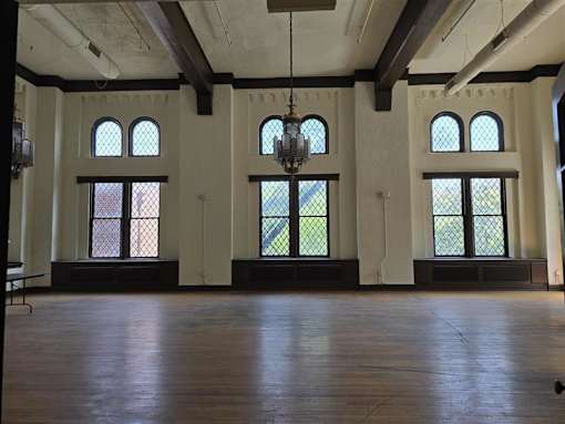 A large room with wooden floors and a chandelier hanging from the ceiling.
