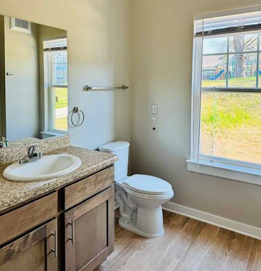 A bathroom with a toilet, sink, and a window.