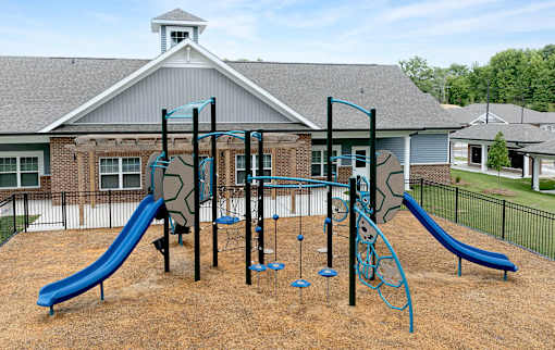 A playground with a blue slide and a green climbing frame.