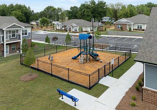 A playground with a blue slide and a brown sandbox.
