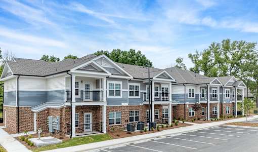 A row of townhouses with a parking lot in front.